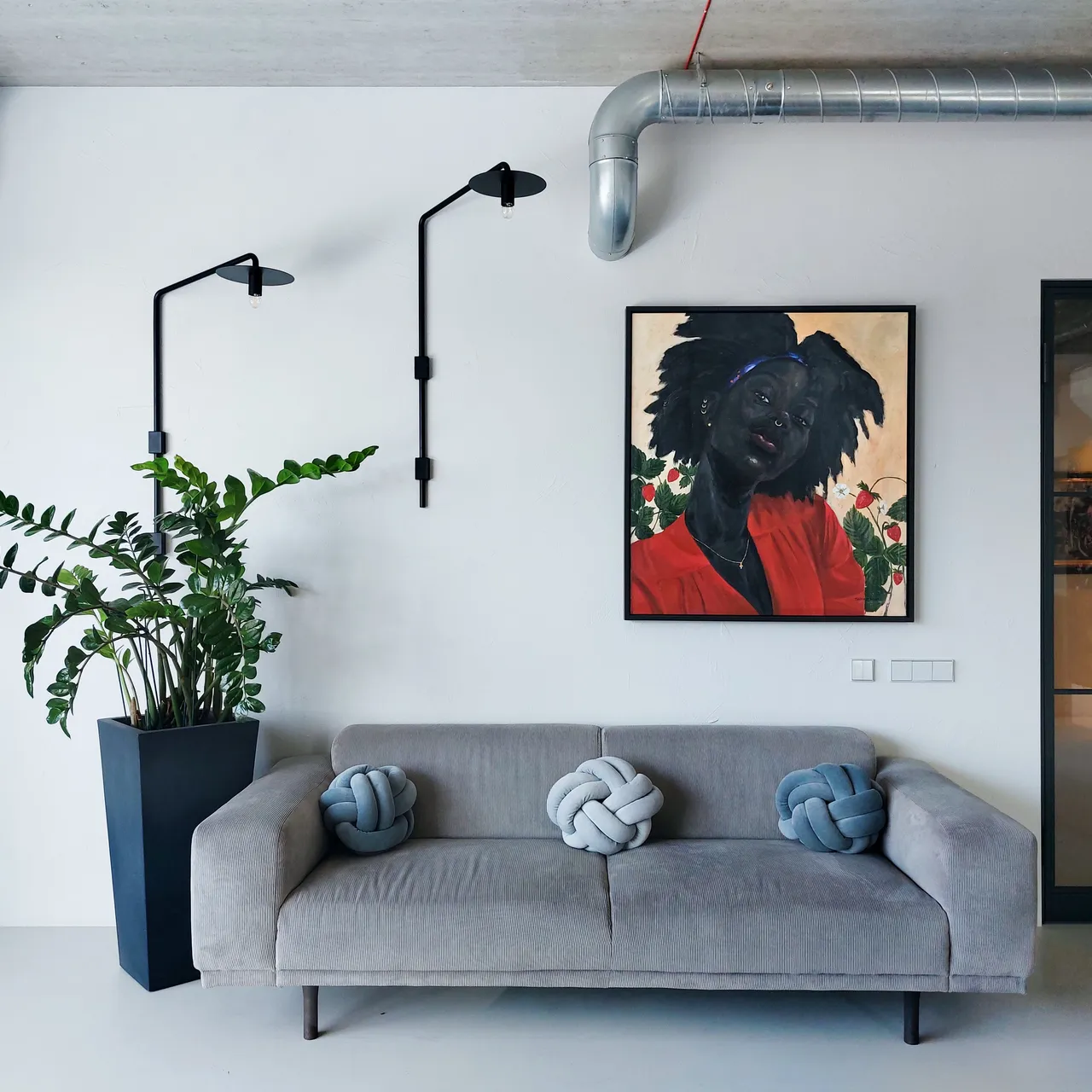 A painting on a white wall above a grey sofa in an office
