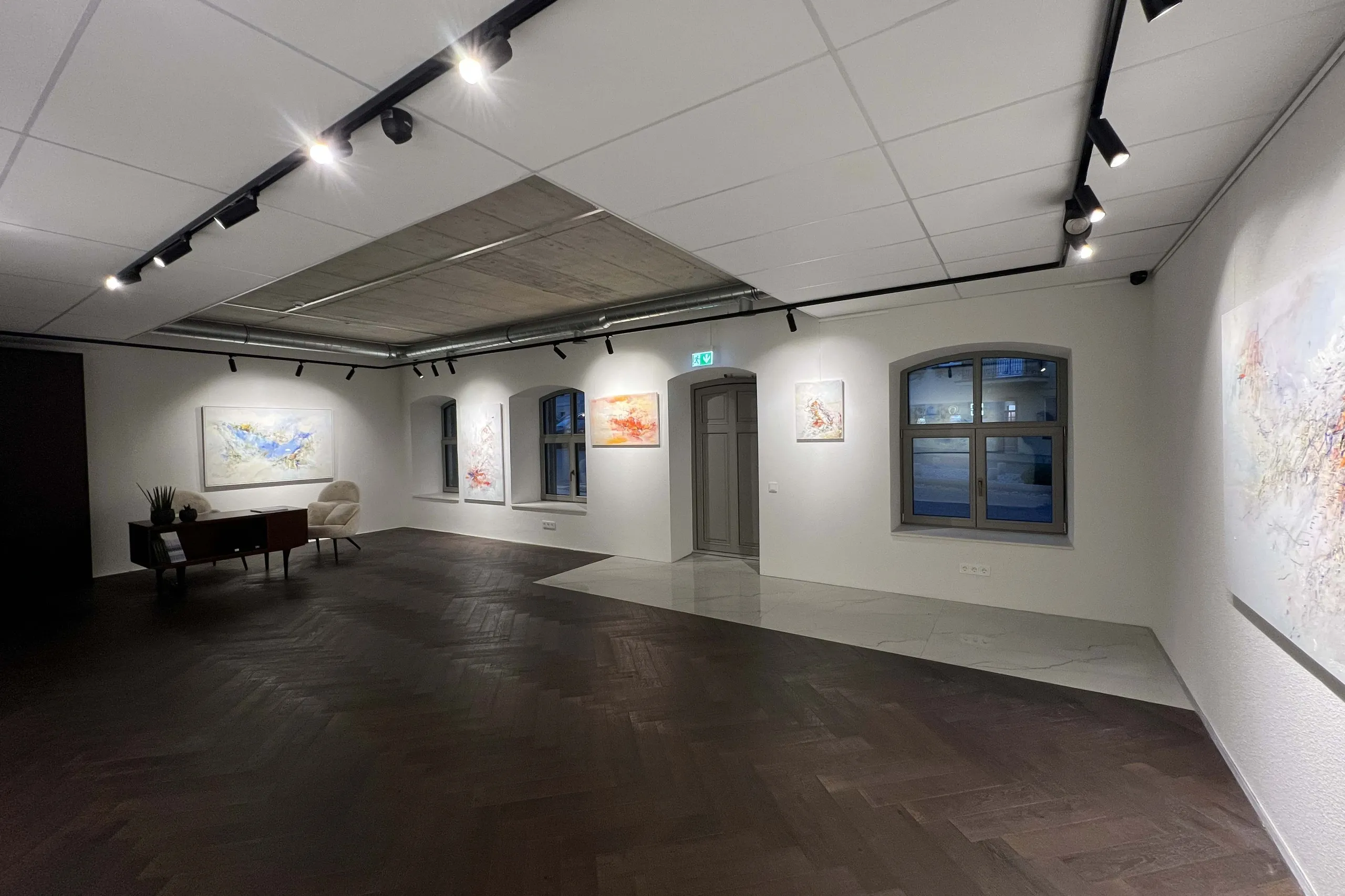 Wide gallery hall with a desk, an armchair and paintings
